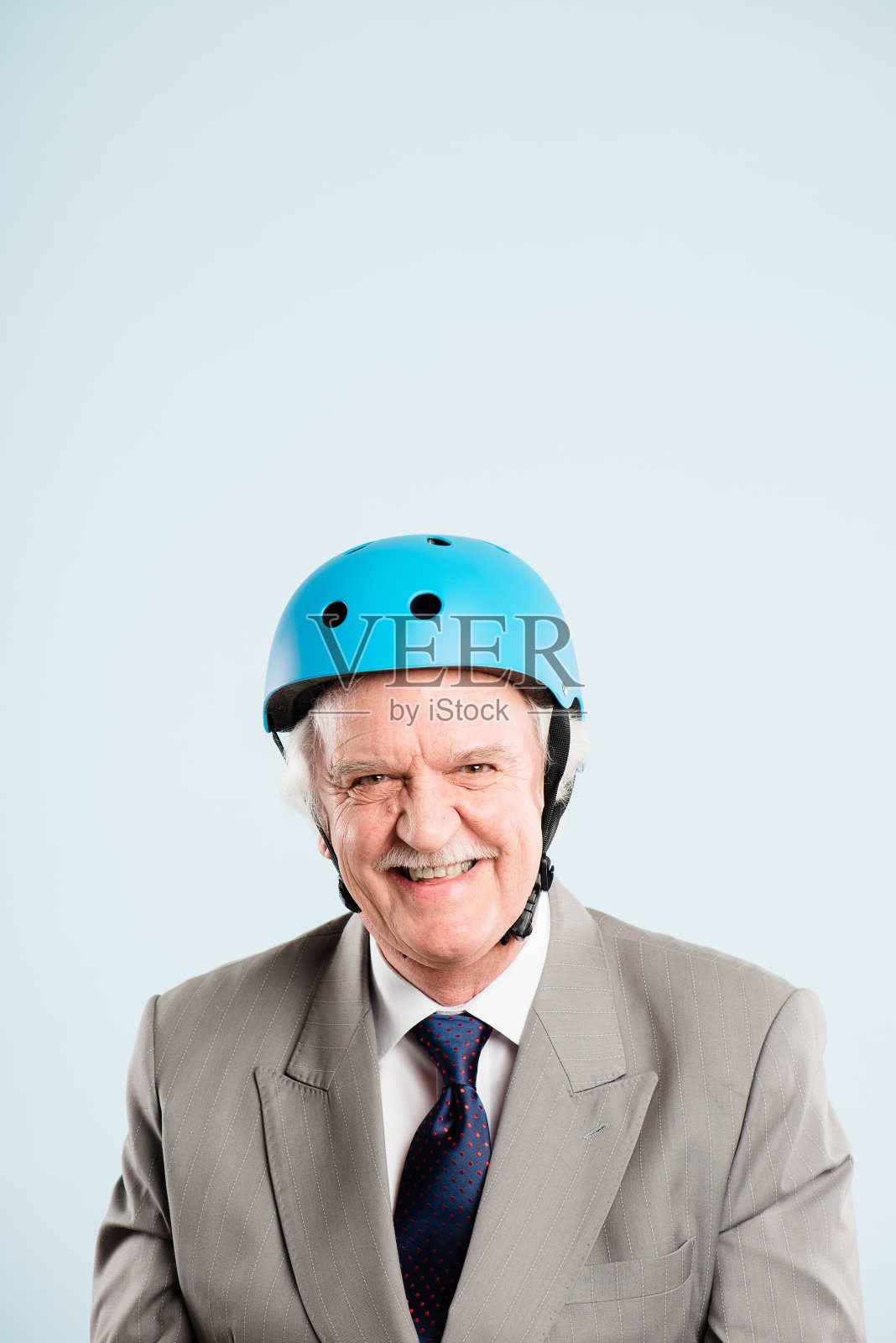 一名年长的男子独自坐在工作室里，戴着头盔摆姿势照片摄影图片