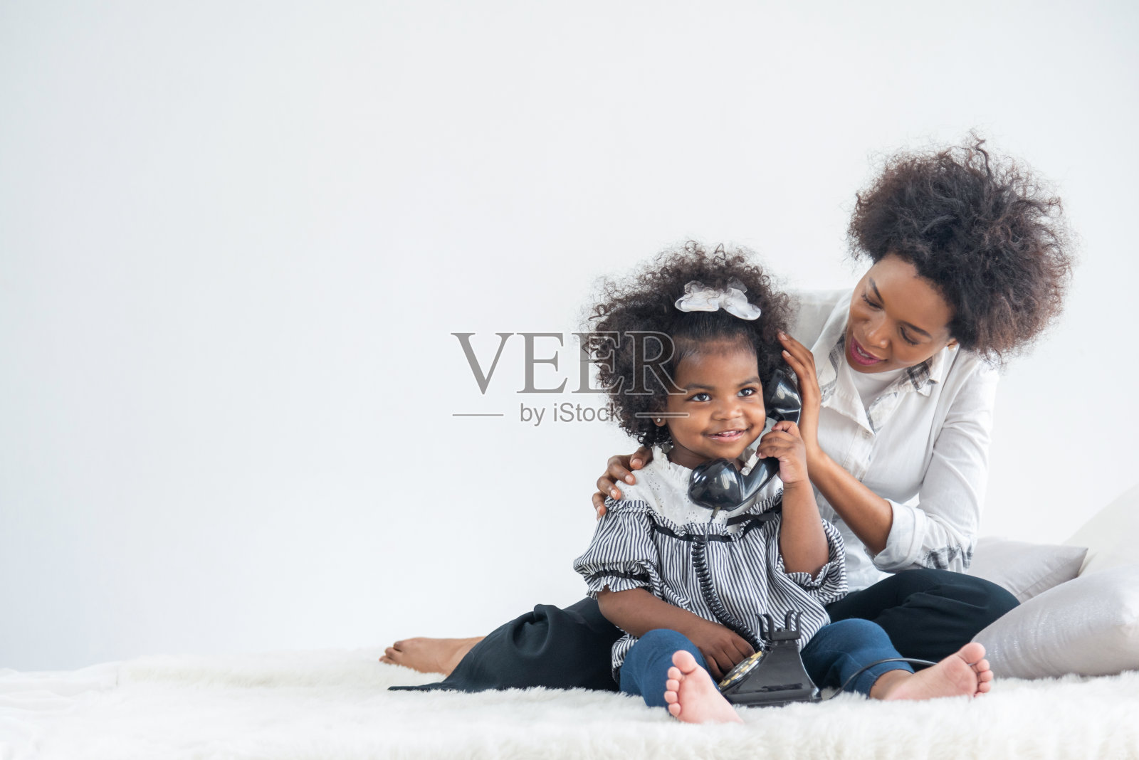 非洲母亲和孩子在讲电话。照片摄影图片