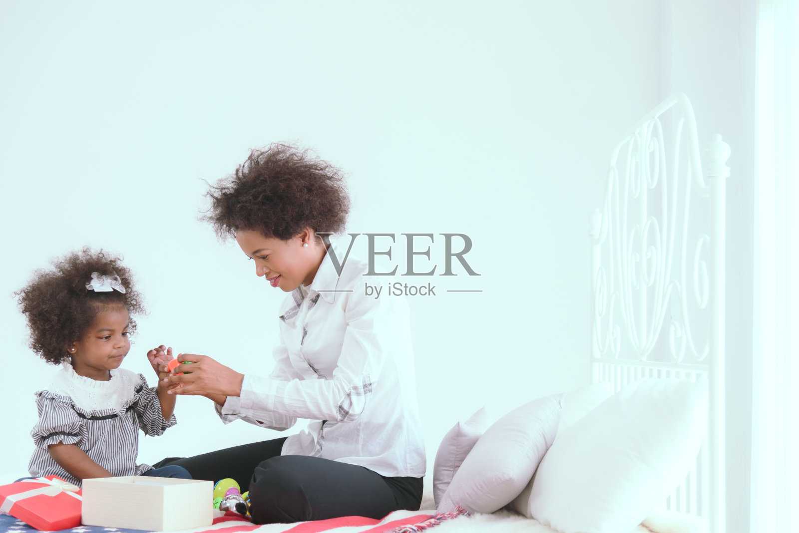 黑人母亲和女儿在房子的卧室里玩玩具。照片摄影图片