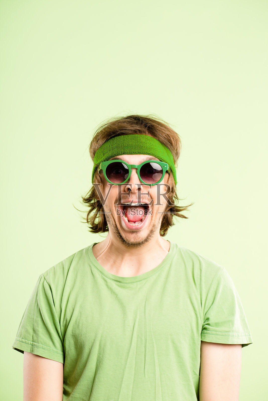 一个英俊的年轻人独自站在演播室里，戴着发带，看起来很兴奋照片摄影图片