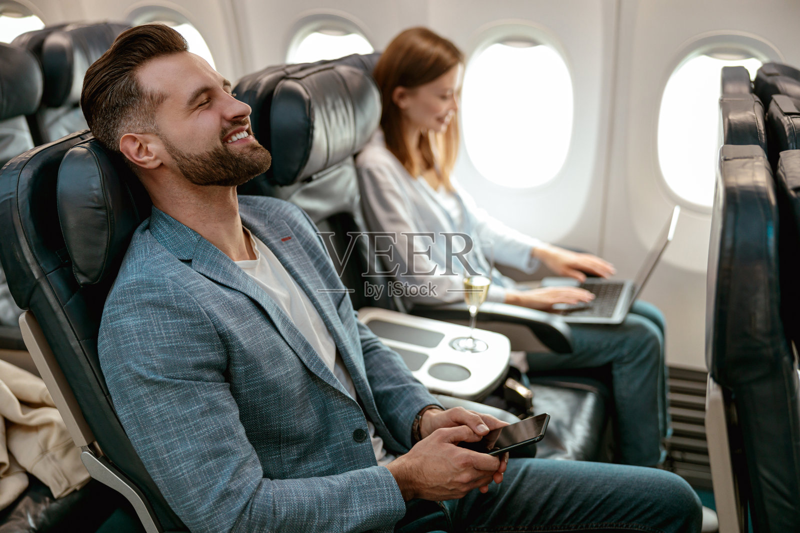 快乐的大胡子男人带着智能手机乘飞机旅行照片摄影图片