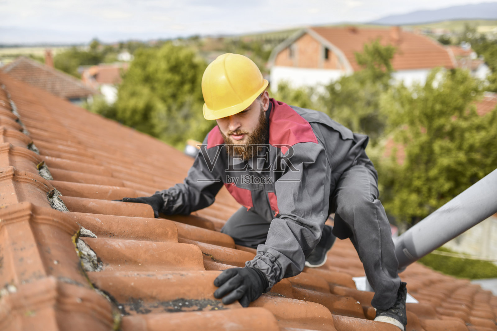 大胡子男工人在屋顶上行走时小心地保持平衡照片摄影图片