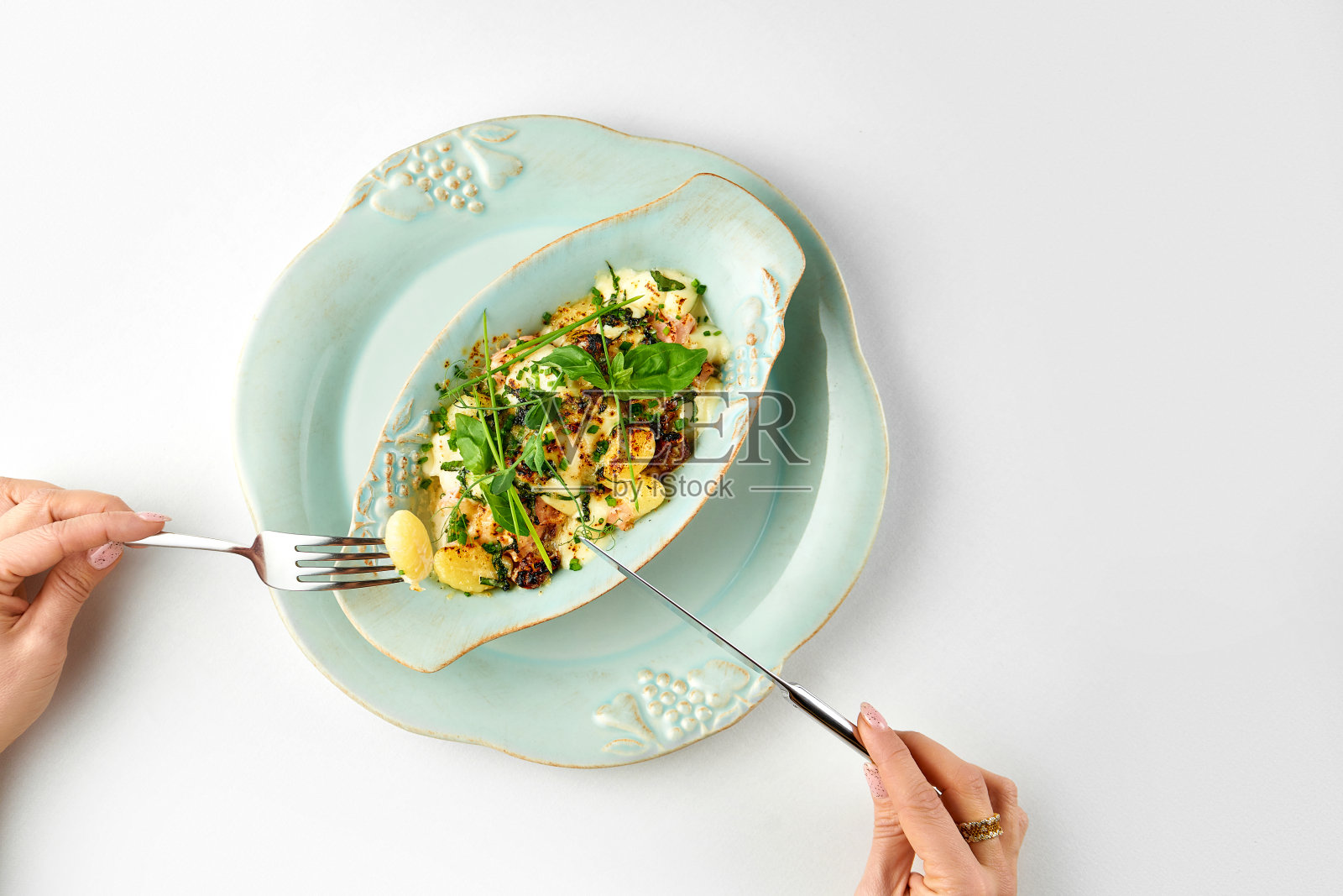 在白色桌布上的盘子里放着奶油烤土豆、奶酪和培根。特写镜头照片摄影图片