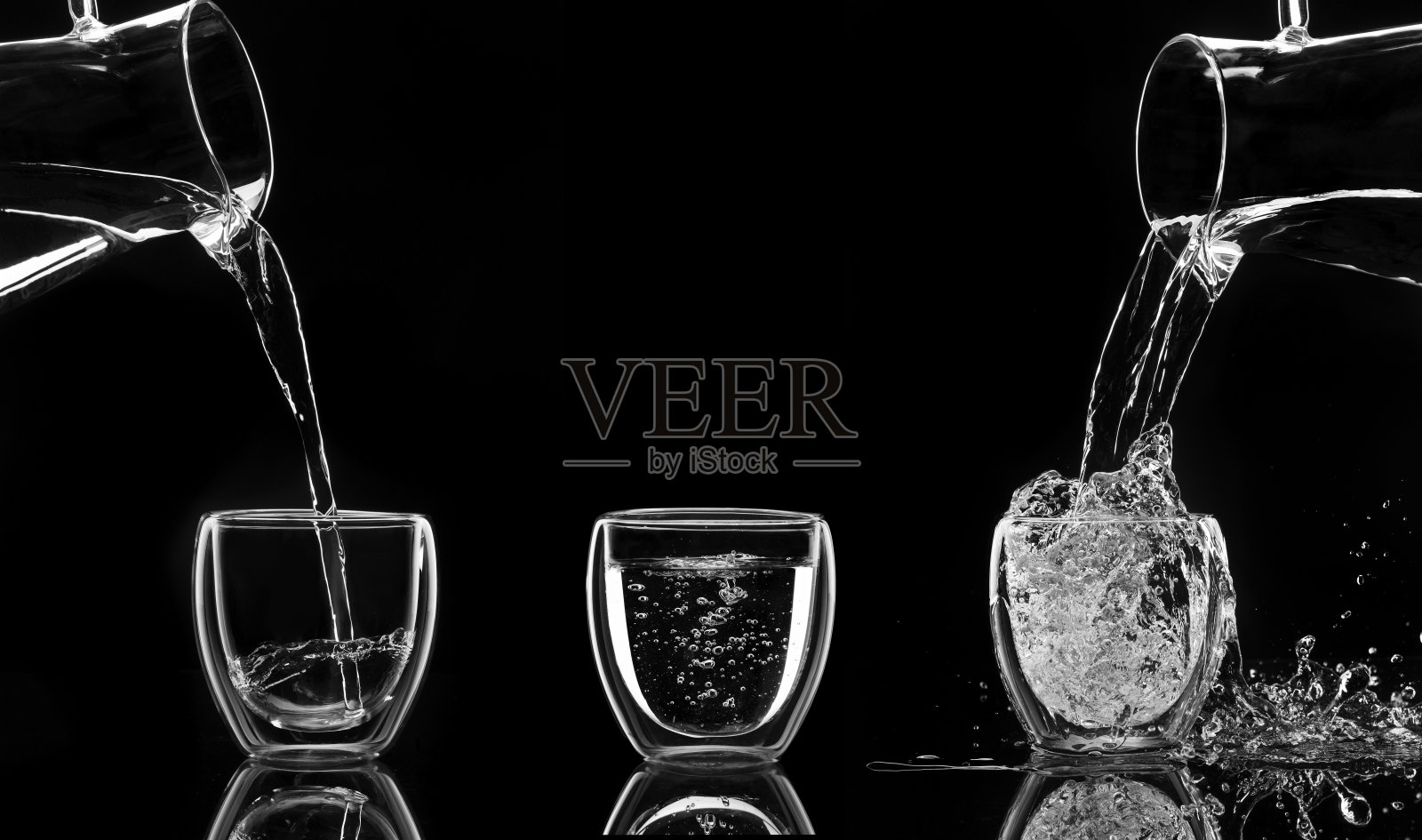 水在黑色的背景下从玻璃瓶中倒入玻璃杯照片摄影图片