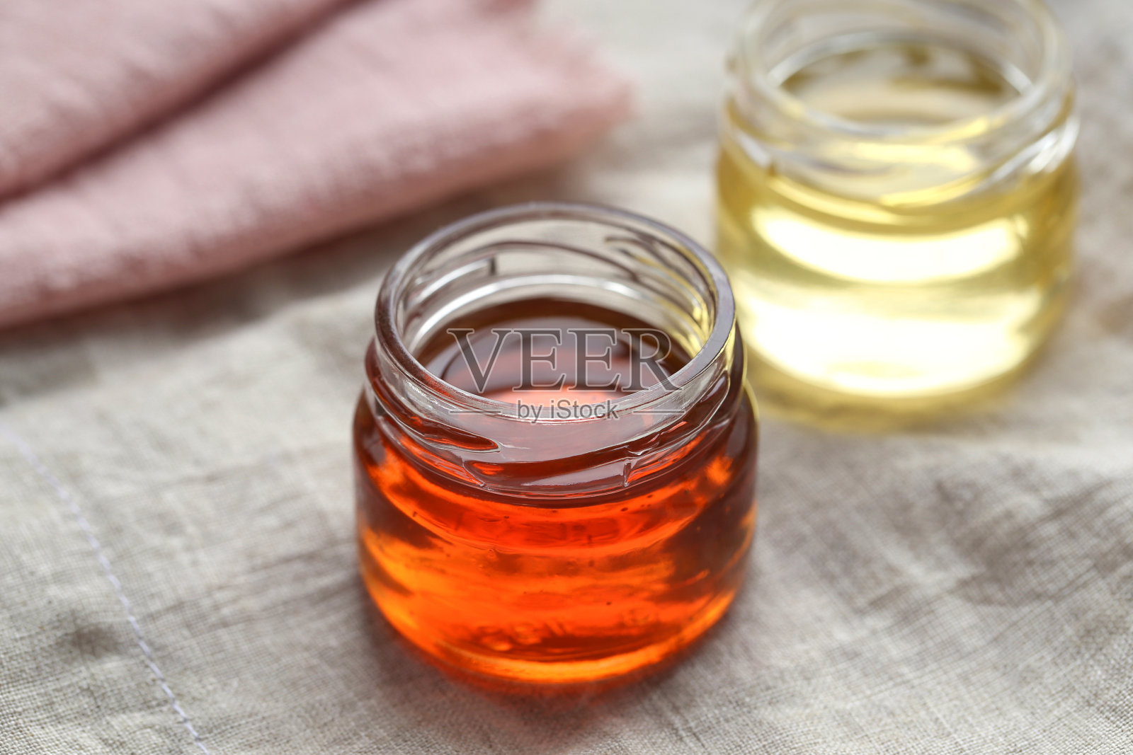 玻璃罐里的荞麦蜂蜜站在浅色的背景上照片摄影图片