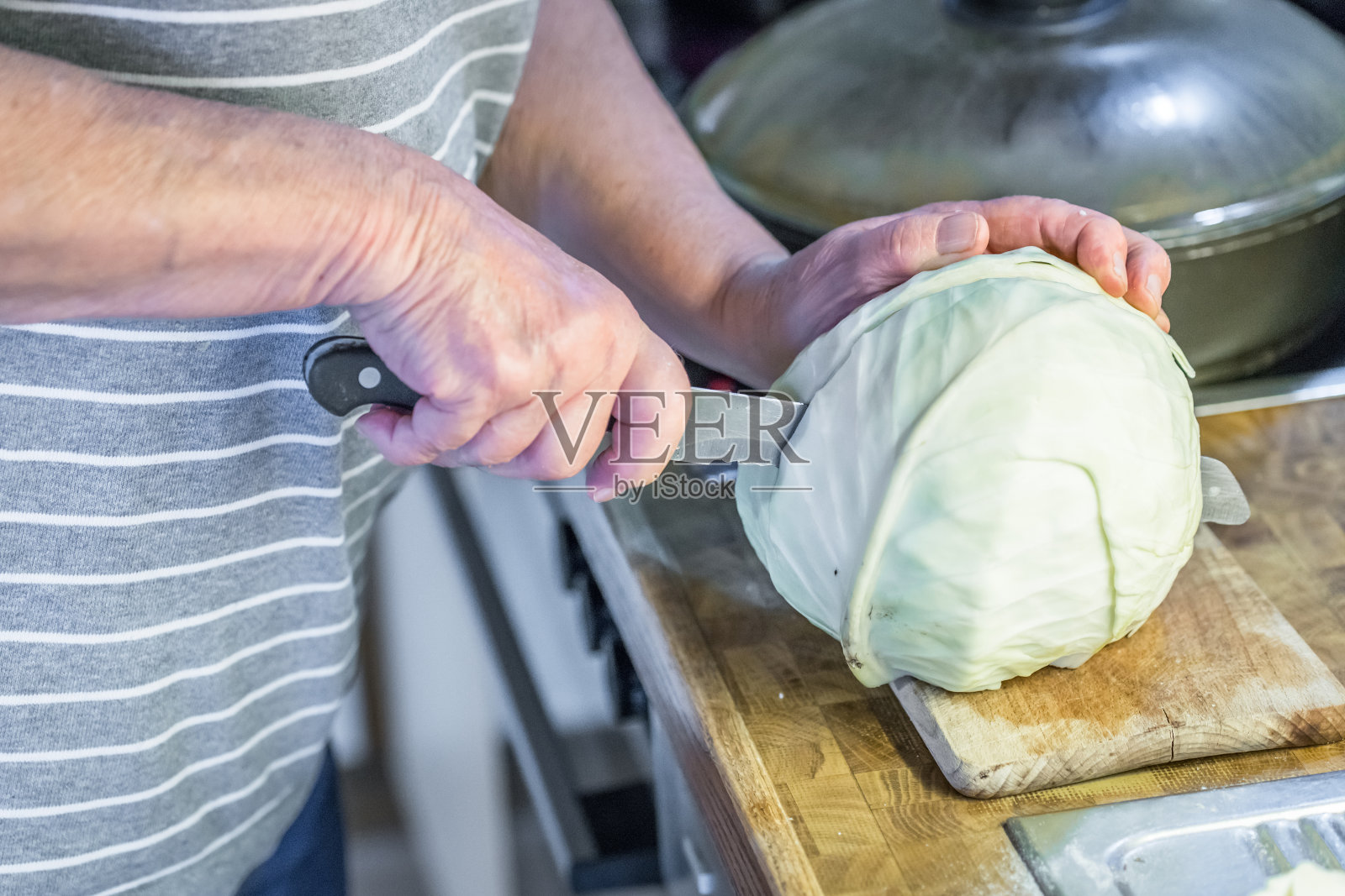 老奶奶在厨房里用刀和木板切着白菜，旁边的水槽和灶台就在工作台上照片摄影图片