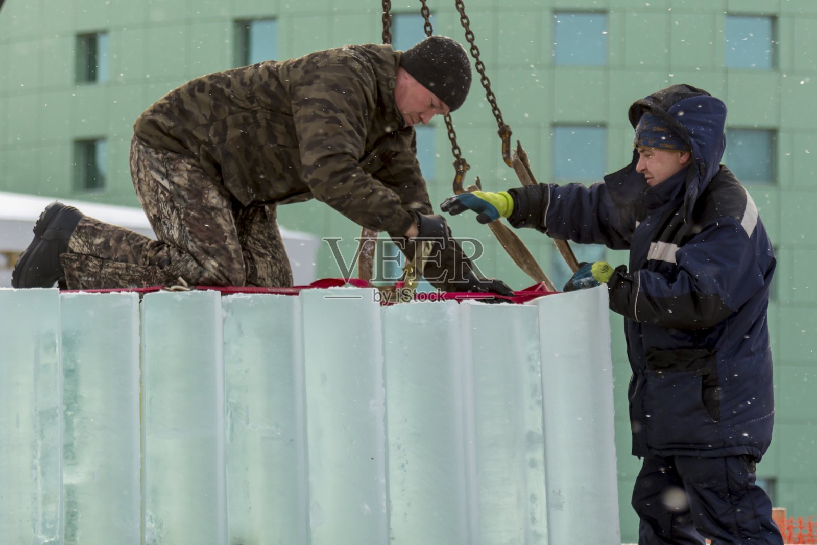 穿冬季工装裤的吊带工人在冰块下挂起吊带照片摄影图片