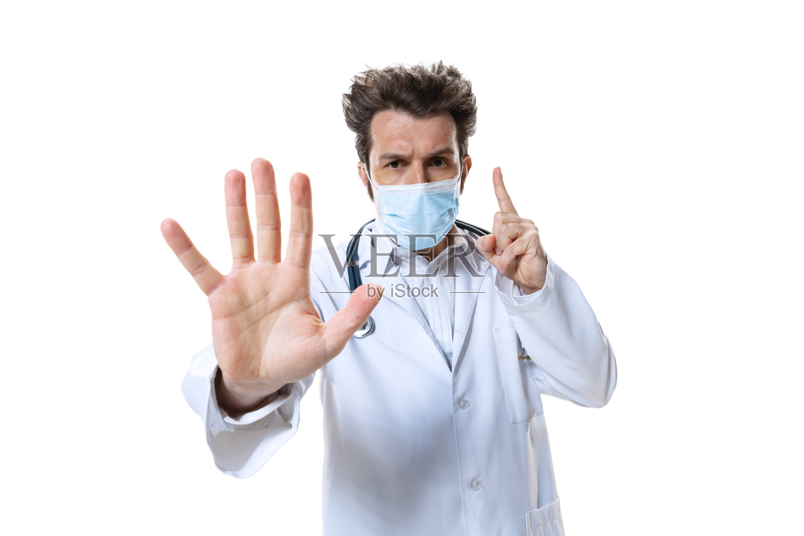 年轻的男性医生，在白色的工作室背景下戴着听诊器和口罩。看起来很难过,认真的。保健和医药的概念，战争，帮助，治疗照片摄影图片