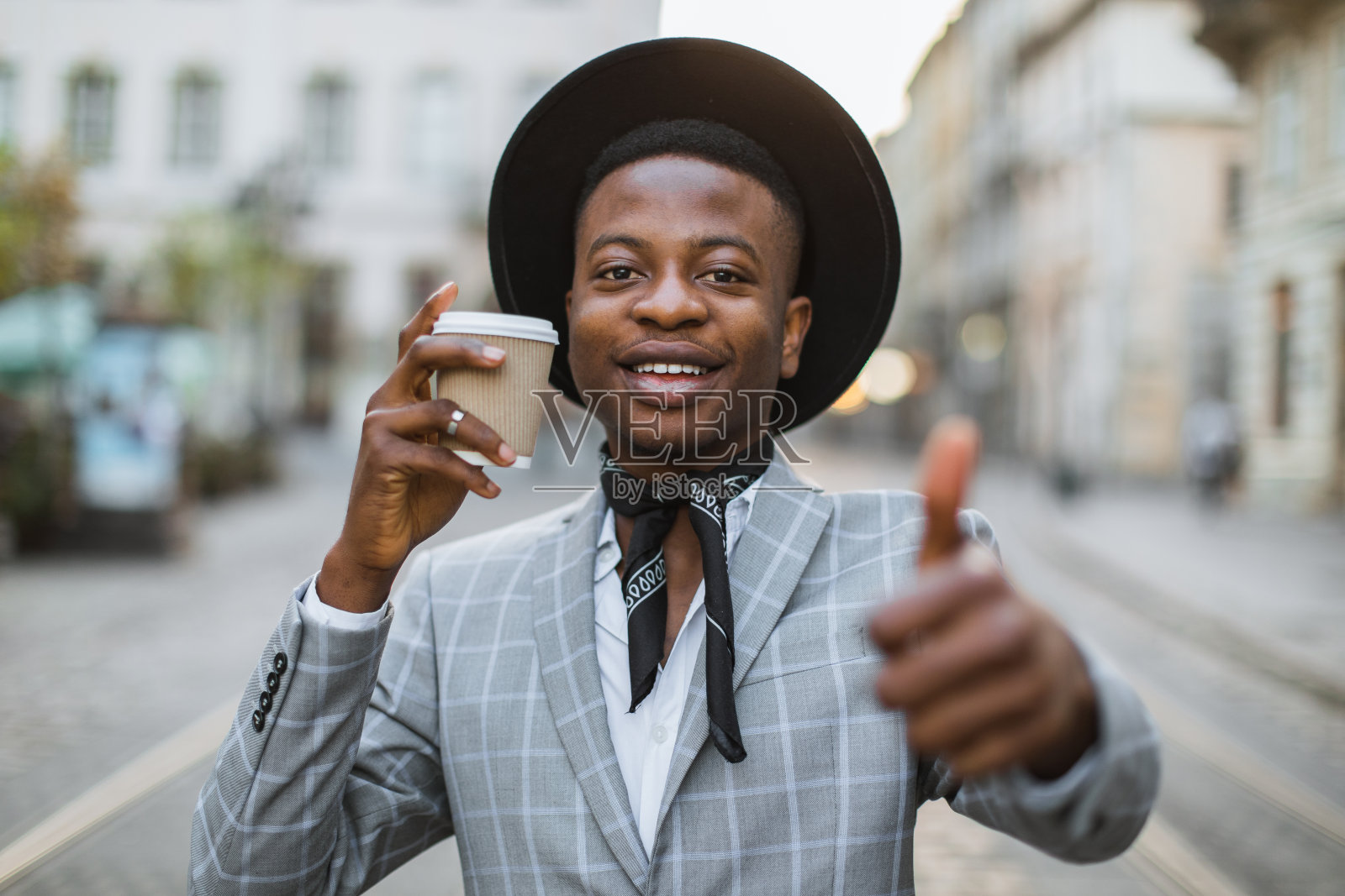 穿着时尚的男人在街上摆姿势喝咖啡照片摄影图片