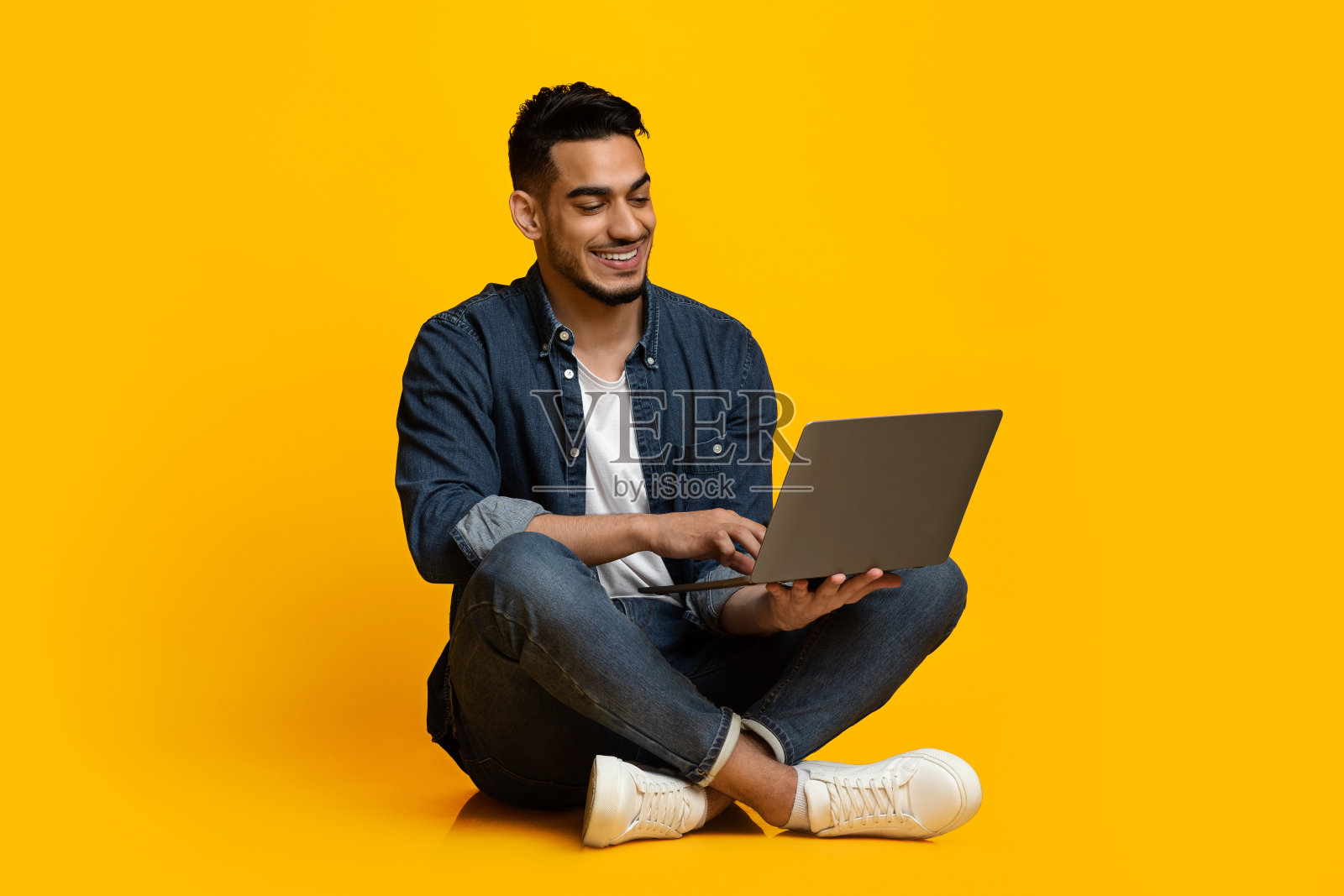 快乐的中东人用现代笔记本，用黄色隔离照片摄影图片