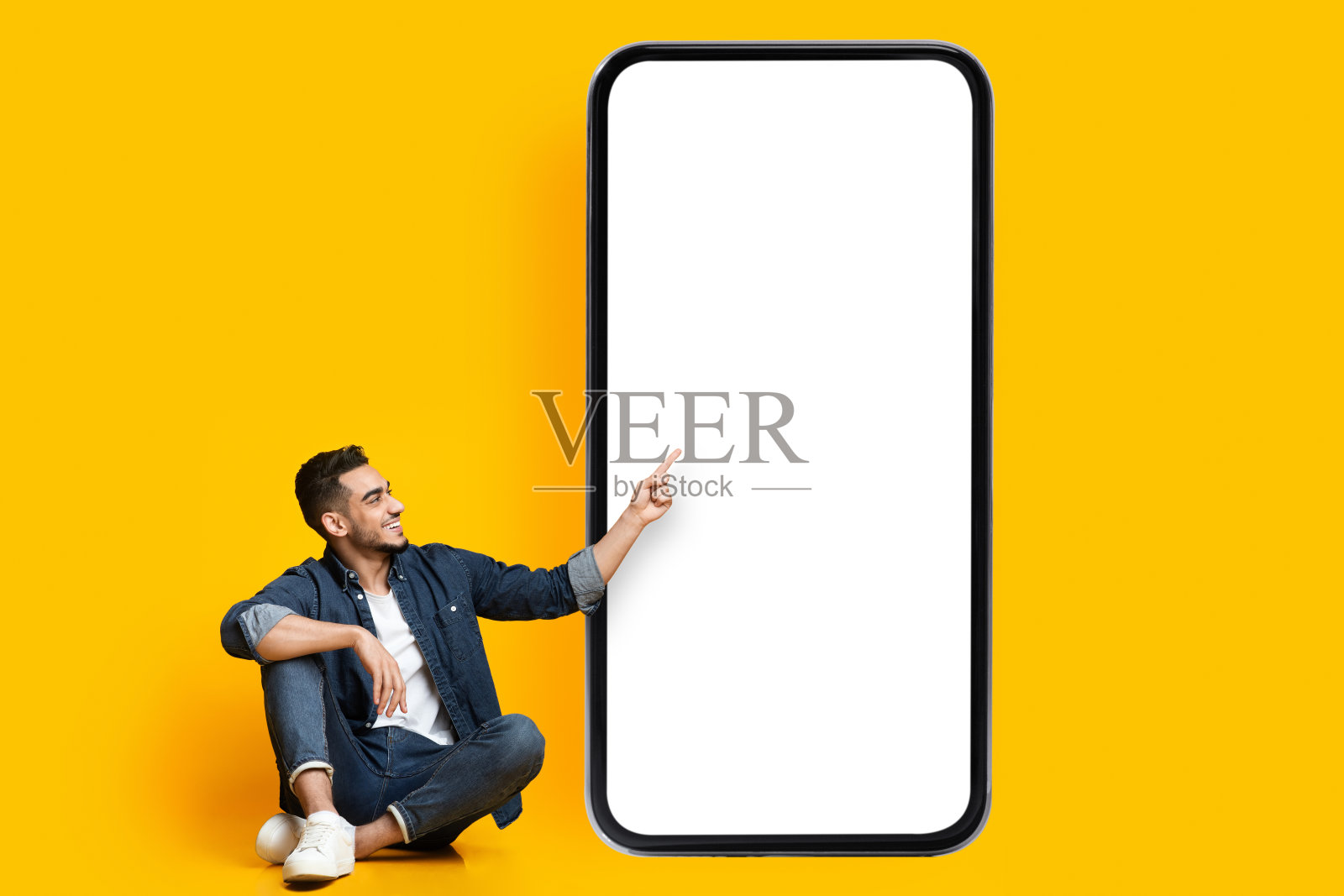 兴高采烈的中东人指着智能手机的空屏幕，模型照片摄影图片