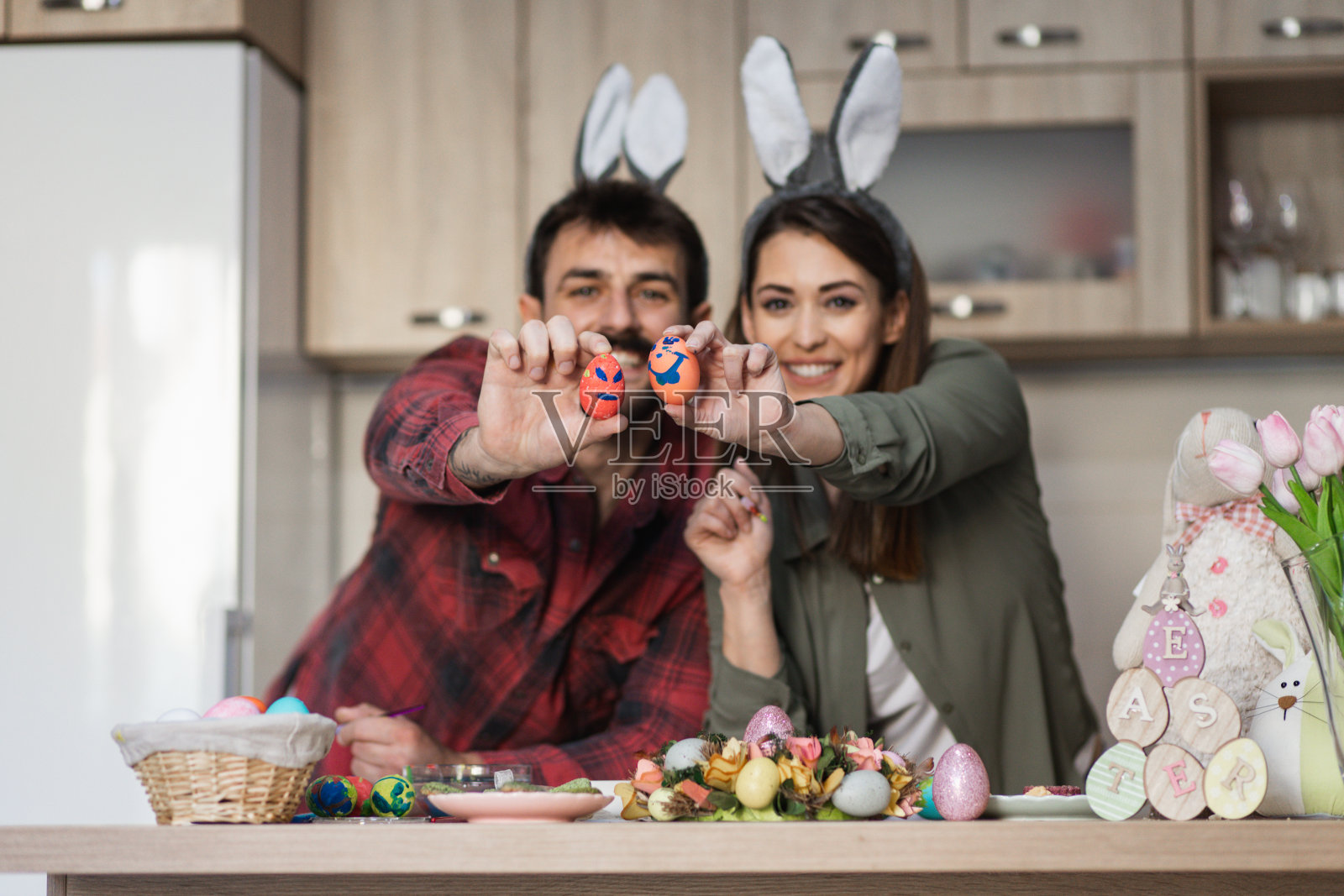 漂亮的年轻夫妇拿着复活节彩蛋，戴着兔子耳朵照片摄影图片
