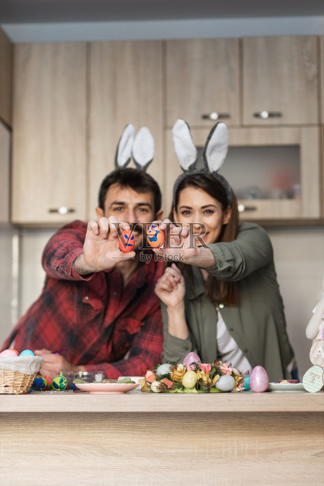 漂亮的年轻夫妇拿着复活节彩蛋，戴着兔子耳朵照片摄影图片