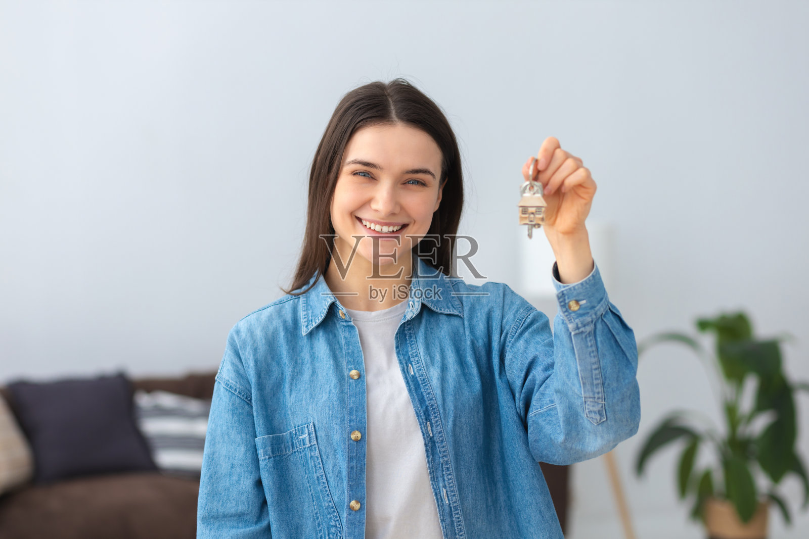 年轻英俊年轻的白人女子拿着钥匙的新家和友好的微笑快乐地看着相机照片摄影图片