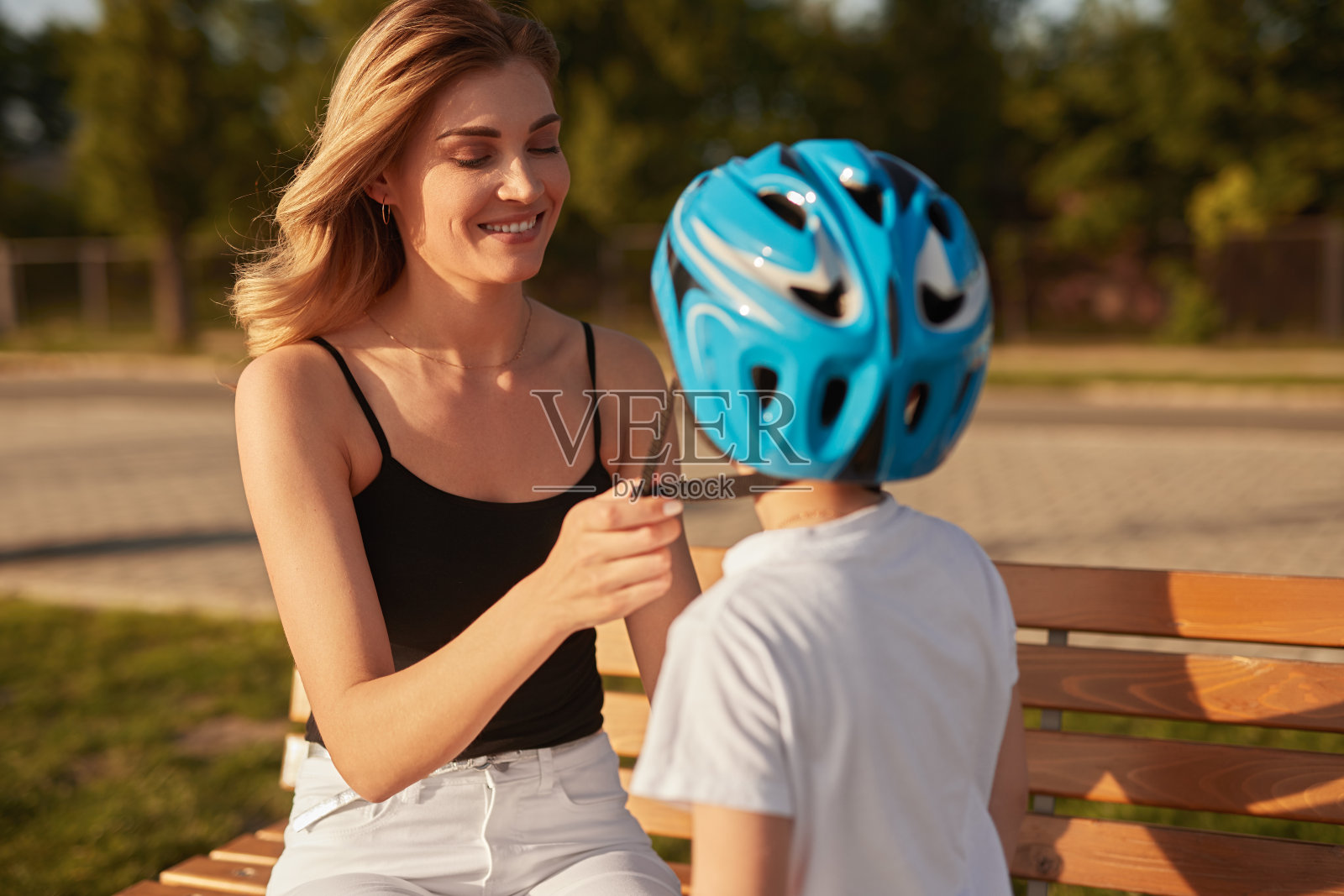 母亲在公园给儿子系头盔照片摄影图片