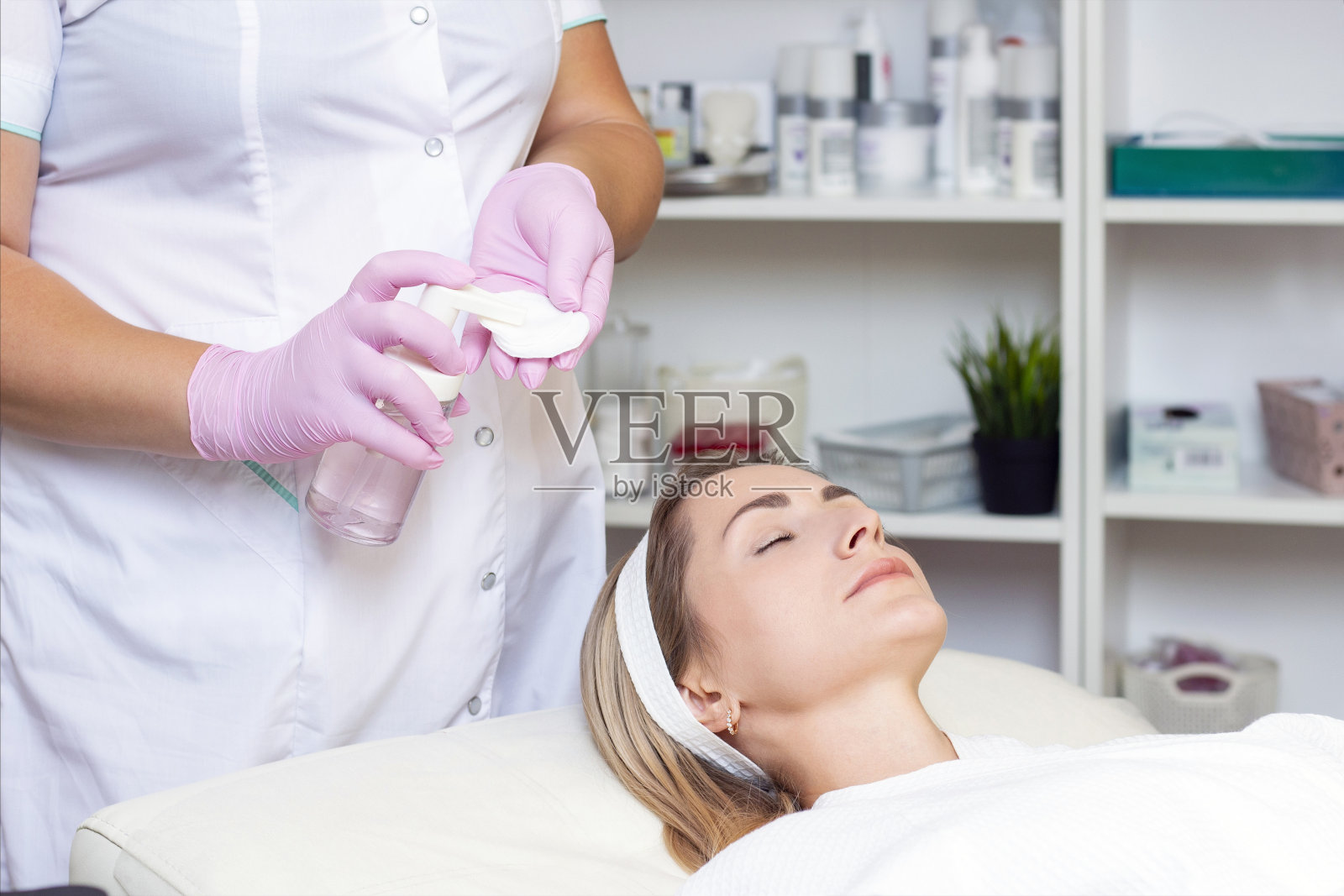 美容。近距离照片可爱的年轻女子与闭着眼睛接受面部清洁程序在美容院。照片摄影图片