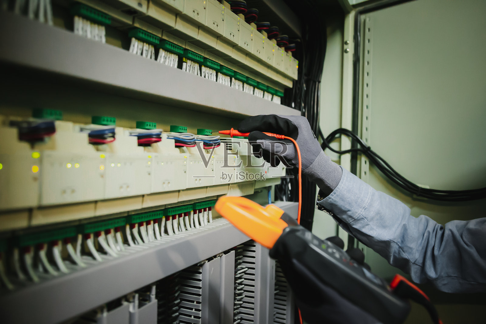 电气工程师用万用表测试电气安装和保护继电器接线。照片摄影图片