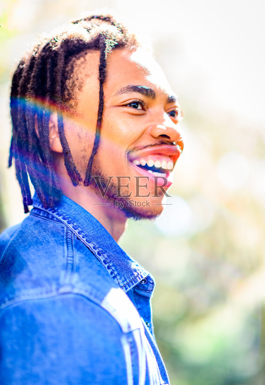 一个英俊的年轻黑人男子在户外拍了一张偷拍的大头照，脸上露出可怕的笑容照片摄影图片