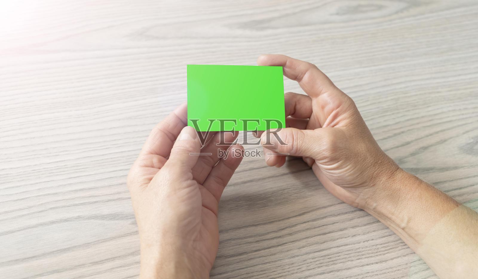 一个女人的手拿着一张没有商标的绿色屏幕名片照片摄影图片