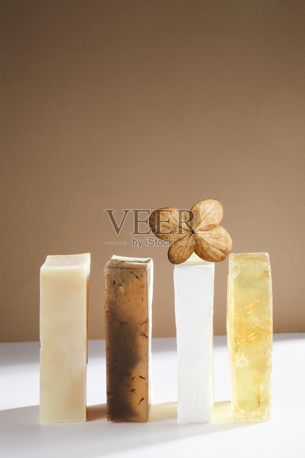 一套美丽的手工制作的天然肥皂与干叶在白色和棕色的背景。有机简约、环保、spa护肤理念。副本的空间。照片摄影图片