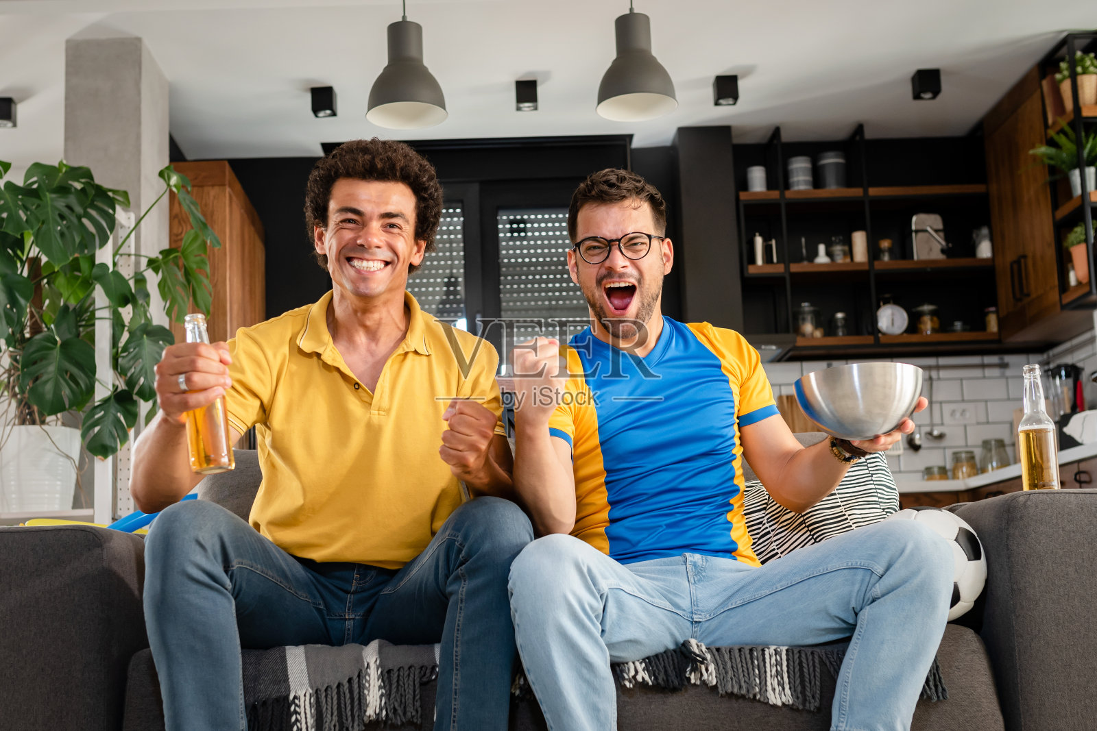 男性朋友在电视上玩游戏。为他们的运动队加油照片摄影图片