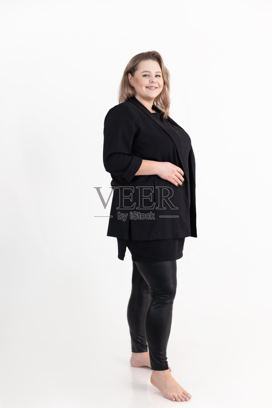 微笑迷人的中年胖胖丰满的女人的肖像长黑发化妆穿黑色开襟羊毛衫。照片摄影图片