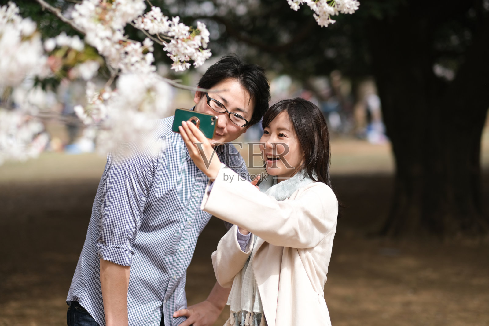 一对情侣在盛开的樱花树下自拍照片摄影图片