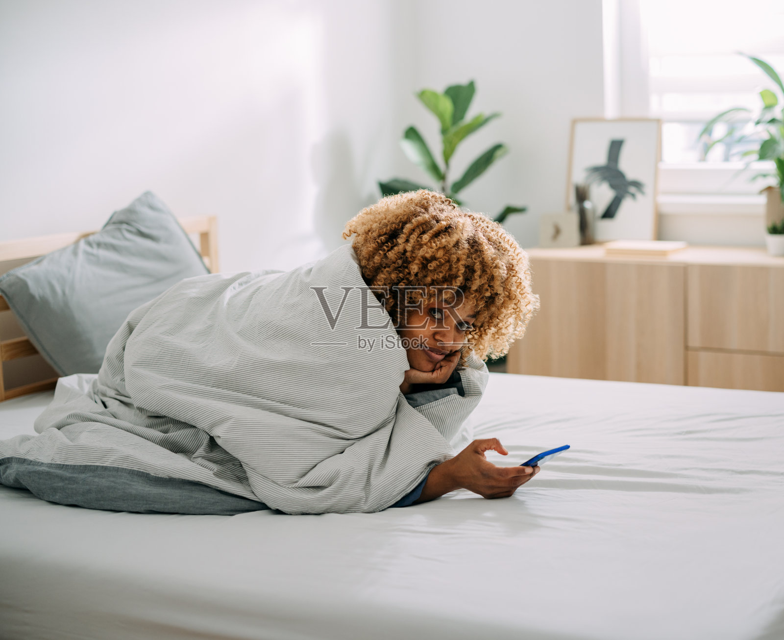 一个快乐的女人在家里的床上用手机的肖像照片摄影图片