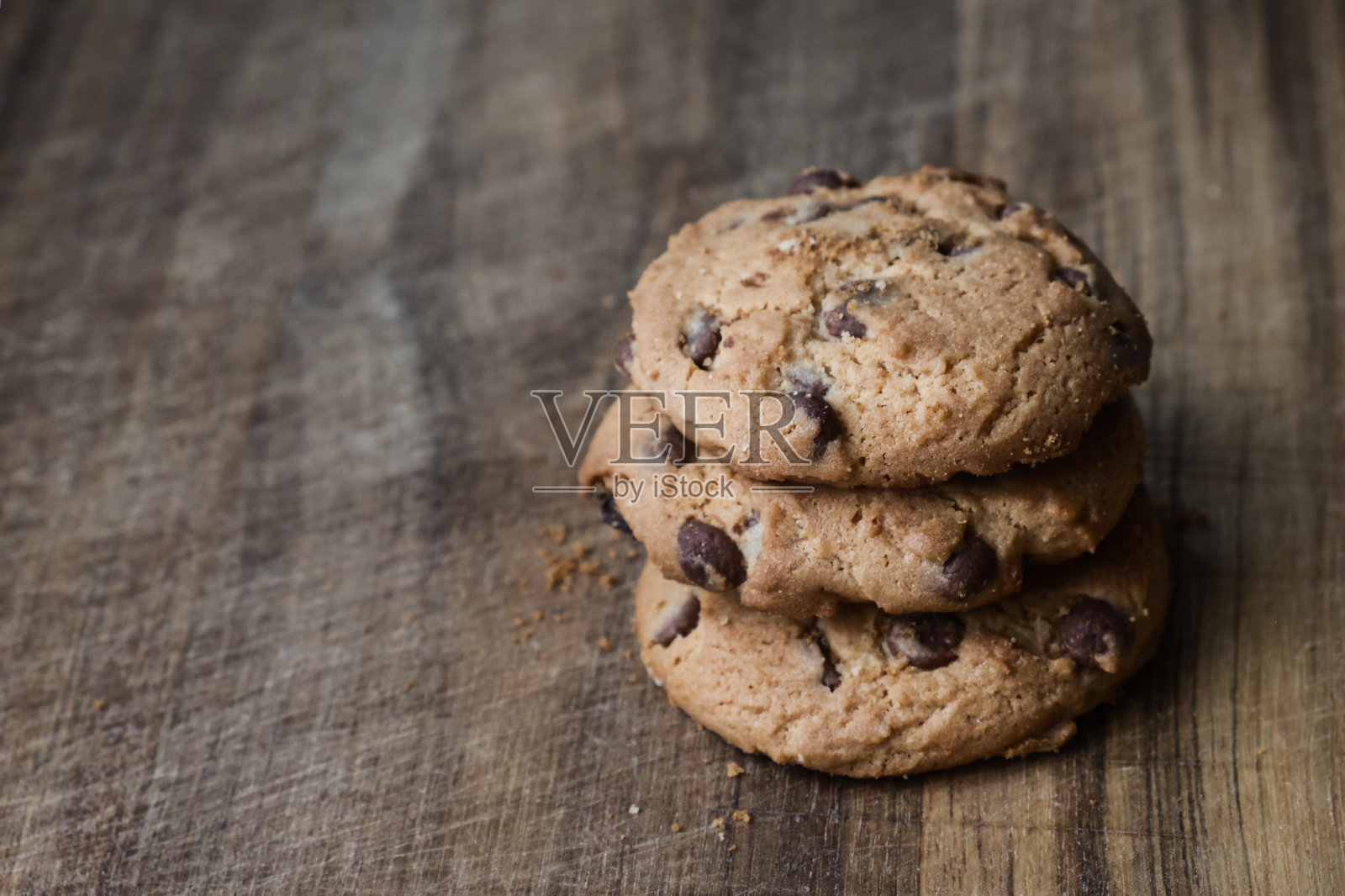 木桌上放着美味的巧克力饼干。木头表面堆着三块巧克力饼干。照片摄影图片