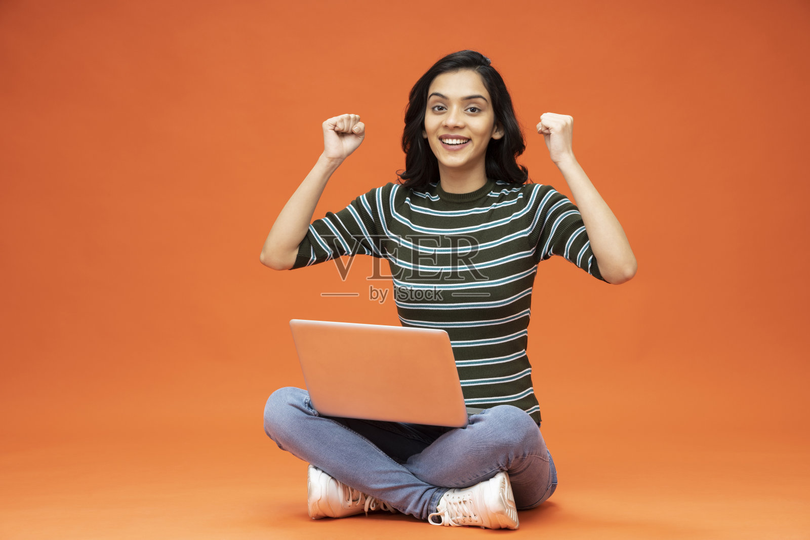 年轻女子坐在地板上，橙色背景的笔记本电脑，库存照片照片摄影图片