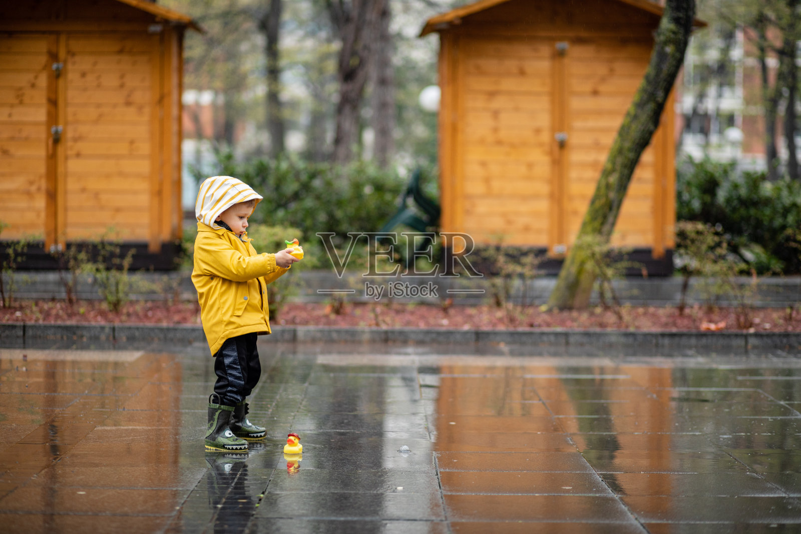 孩子在水坑里玩橡皮鸭照片摄影图片