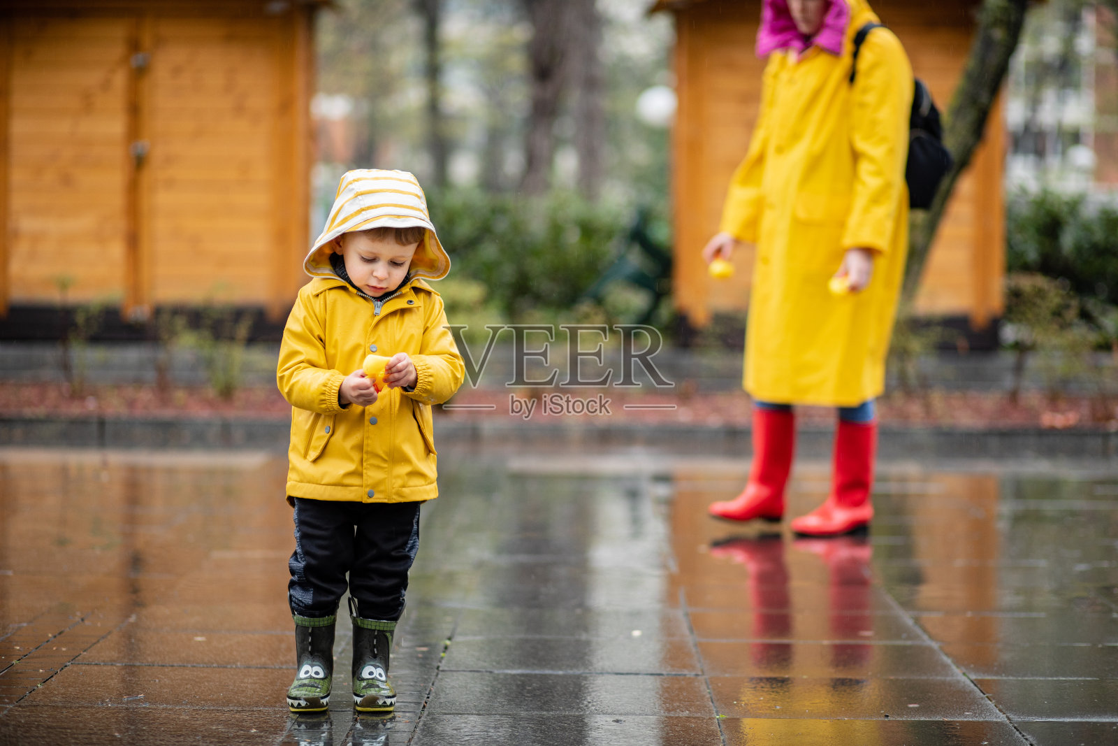 孩子在水坑里玩橡皮鸭照片摄影图片