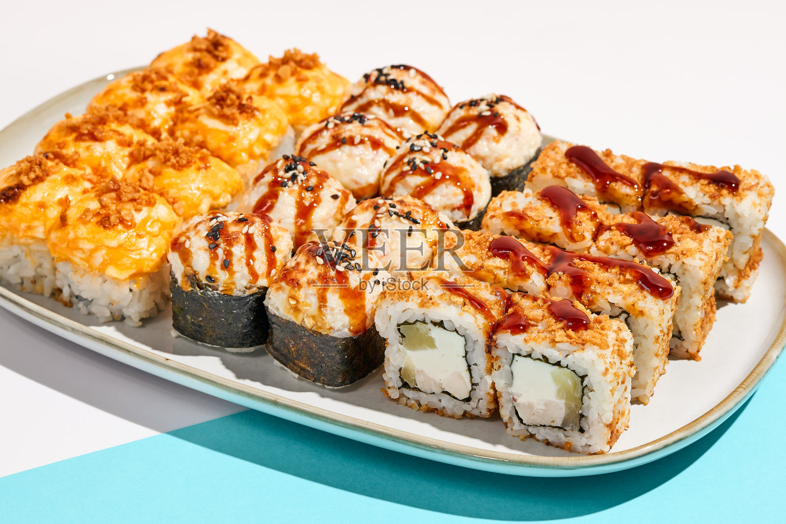 一套陶瓷餐具上的热寿司。极简风格的烘焙寿司。现代概念中的天妇罗翻滚。现代风格的日式菜单。照片摄影图片