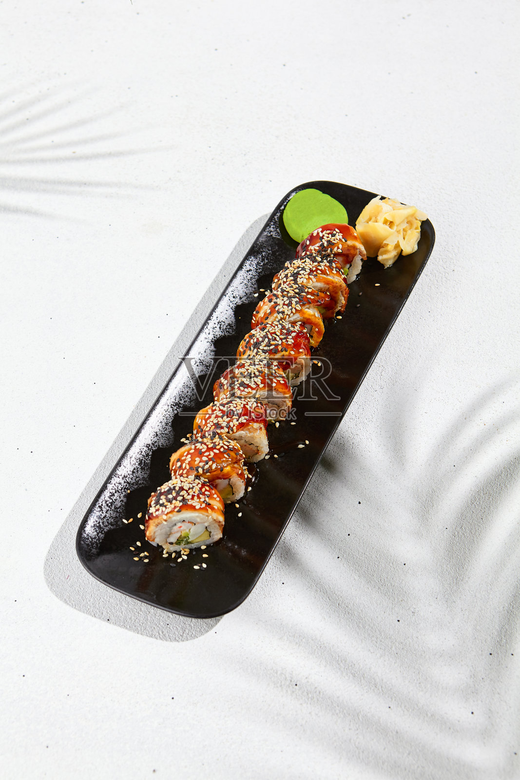 现代亚洲食物-寿司卷与鳗鱼在黑色盘子上白色混凝土背景。加拿大maki，外面是鳗鱼，里面是牛油果，奶酪和虾。鳗鱼寿司。融合寿司菜单。照片摄影图片