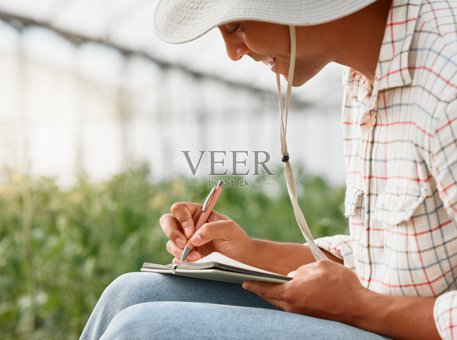 拍摄的是一个年轻人在农场的温室里工作时写笔记照片摄影图片