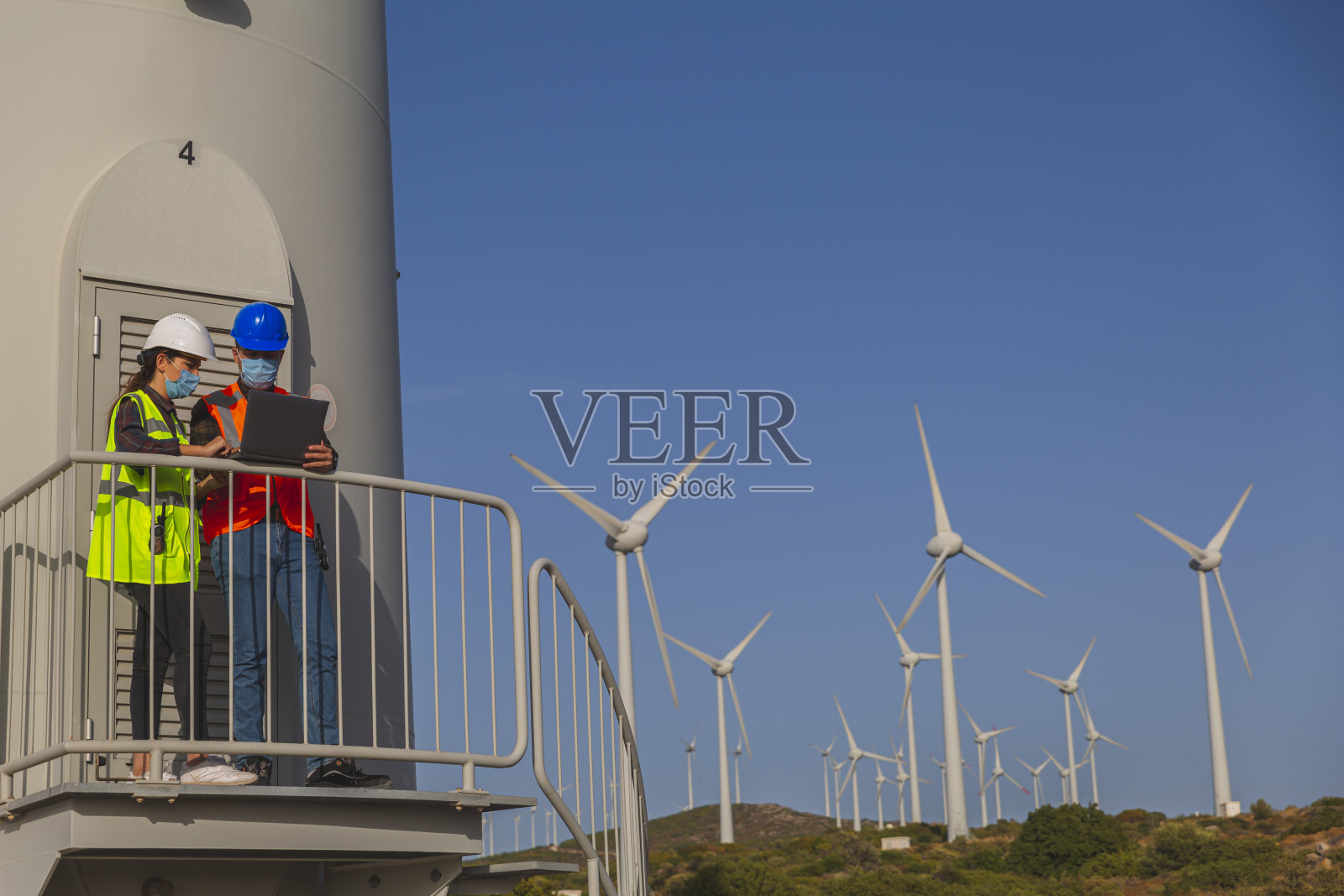 在新冠肺炎疫情爆发后，电气工程师、女性和技术商人戴着外科口罩工作，在大风中站在数字平板电脑旁。照片摄影图片