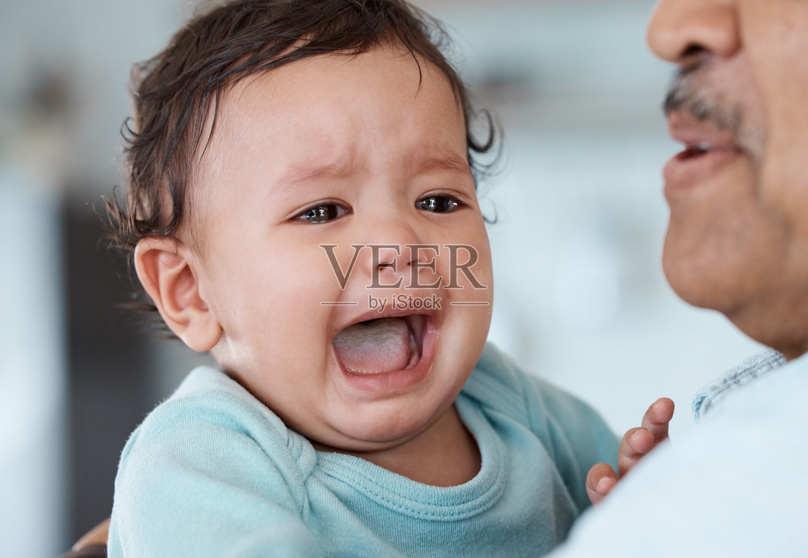 这张照片拍摄的是一个不认识的男人抱着哭泣的孙子在家里照片摄影图片