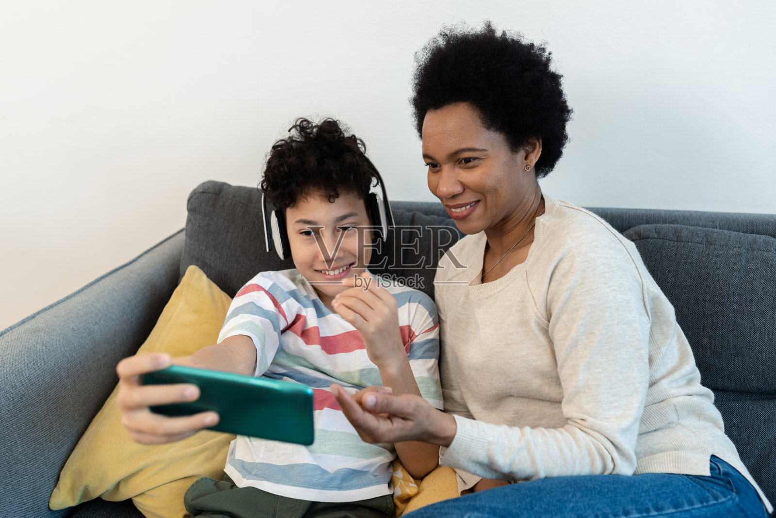 一位非裔美国妇女和她的小儿子在看手机照片摄影图片