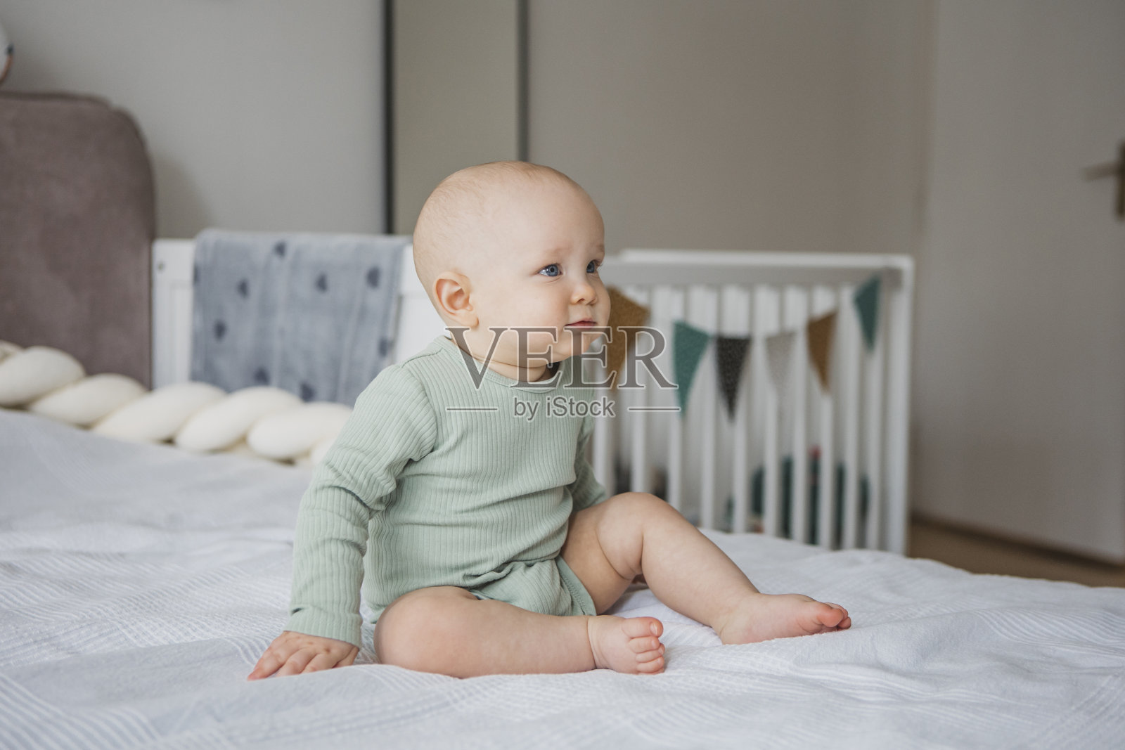 可爱的赤脚孩子坐在床上微笑照片摄影图片