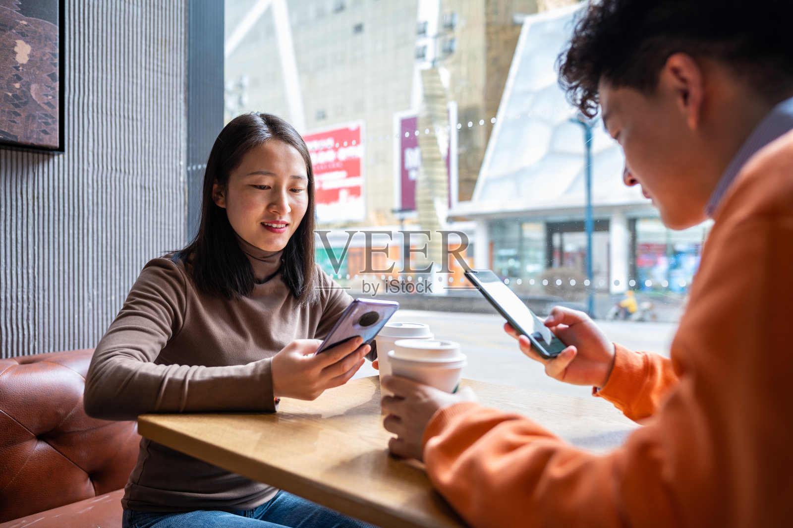 亚洲年轻异性恋夫妇在咖啡店使用智能手机照片摄影图片