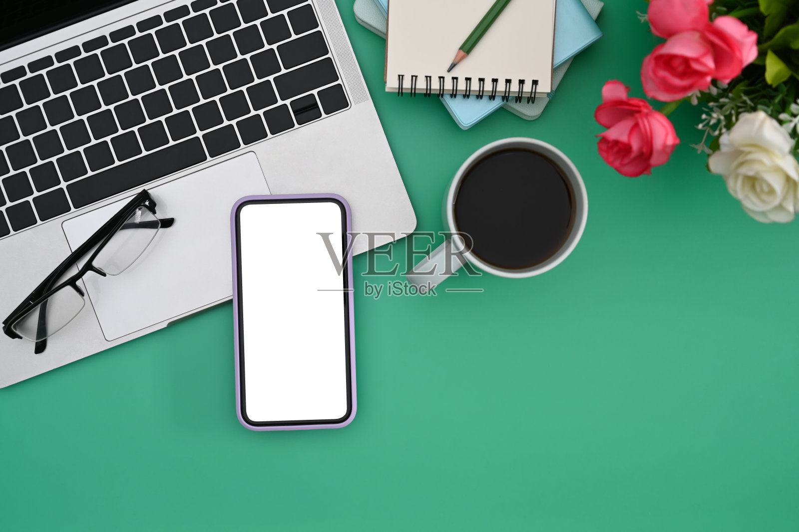 女性的工作场所，电脑笔记本电脑，智能手机，咖啡杯和花盆的绿色背景。照片摄影图片