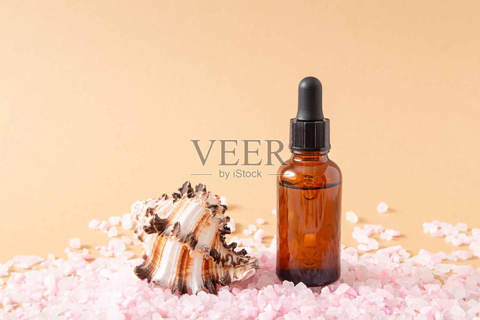 滴鼻深色玻璃化妆品瓶模拟，粉红色的海盐和贝壳在浅棕色的背景。环保护理有机产品。美容、水疗理念。副本的空间。照片摄影图片