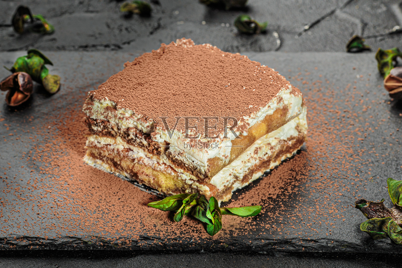 传统意大利甜品提拉米苏与薄荷在黑板上。照片摄影图片