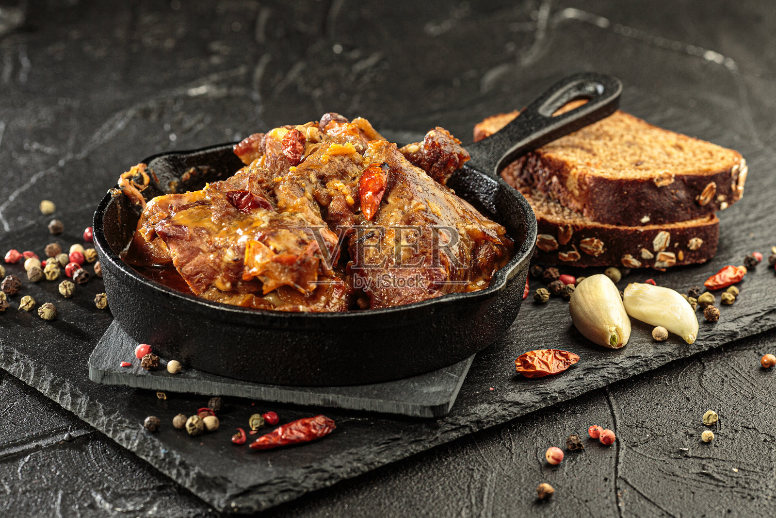 猪肉炖在黑色背景的煎锅上，近距离观看照片摄影图片