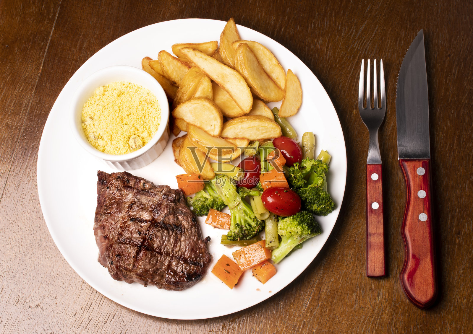 巴西餐，多汁的牛排，蔬菜，乡村土豆和法罗法的顶视图照片摄影图片