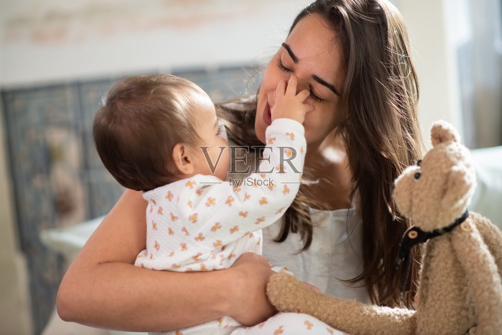 可爱的小男孩在床上摸着妈妈的脸照片摄影图片