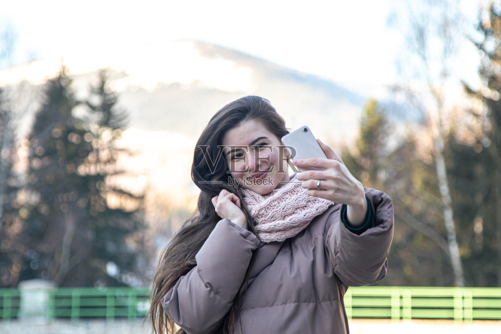一名年轻女子在山里散步时自拍。照片摄影图片