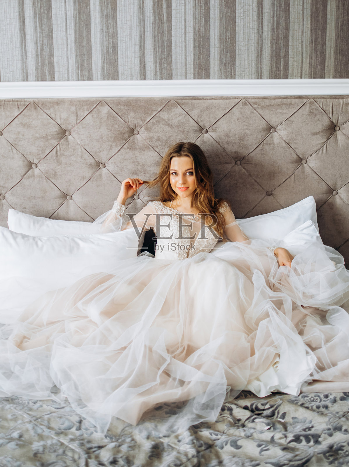 一位令人难以置信的新娘坐在她卧室的床上。早上的新娘。照片摄影图片