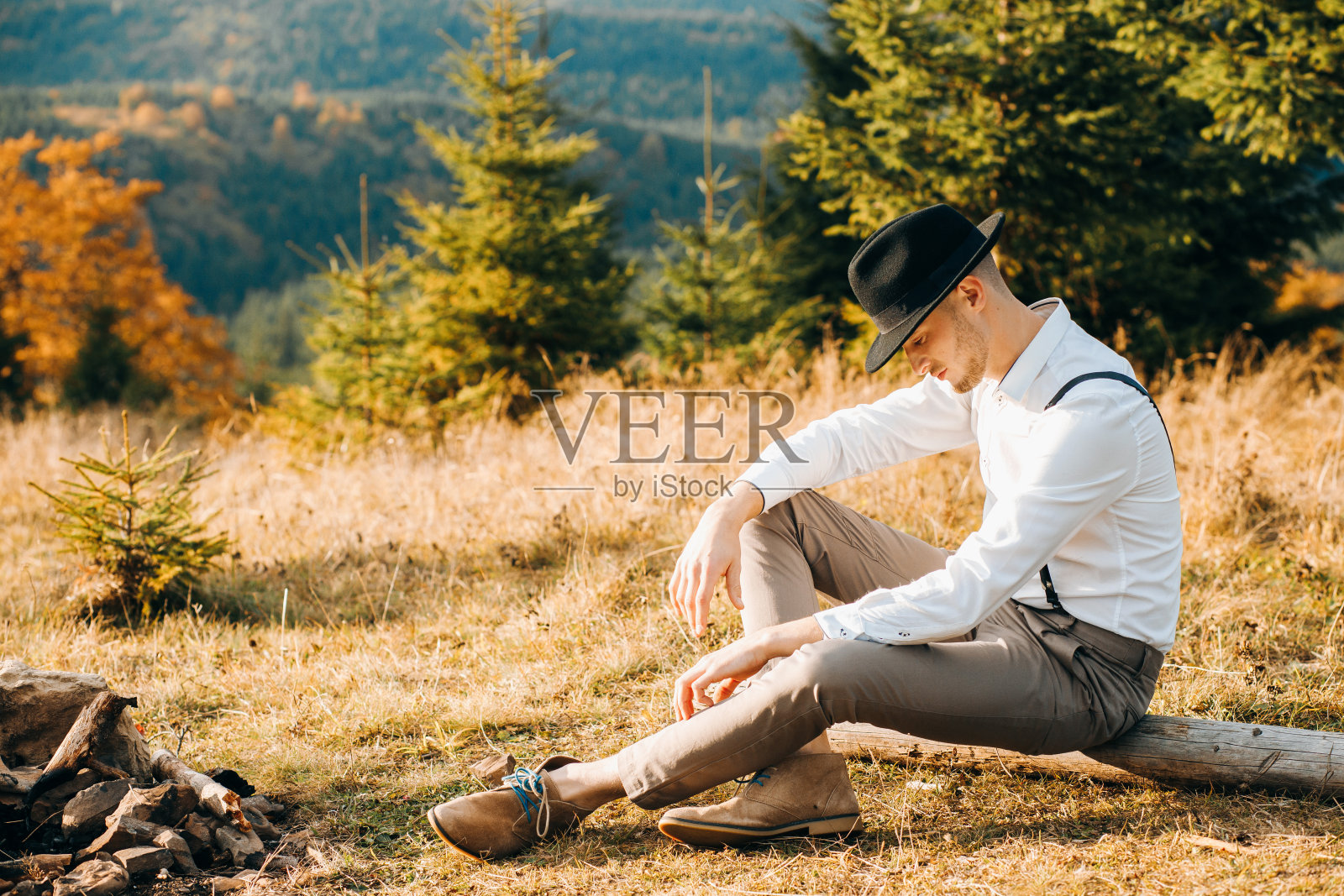 戴着黑帽子的可爱男孩坐在树枝上照片摄影图片