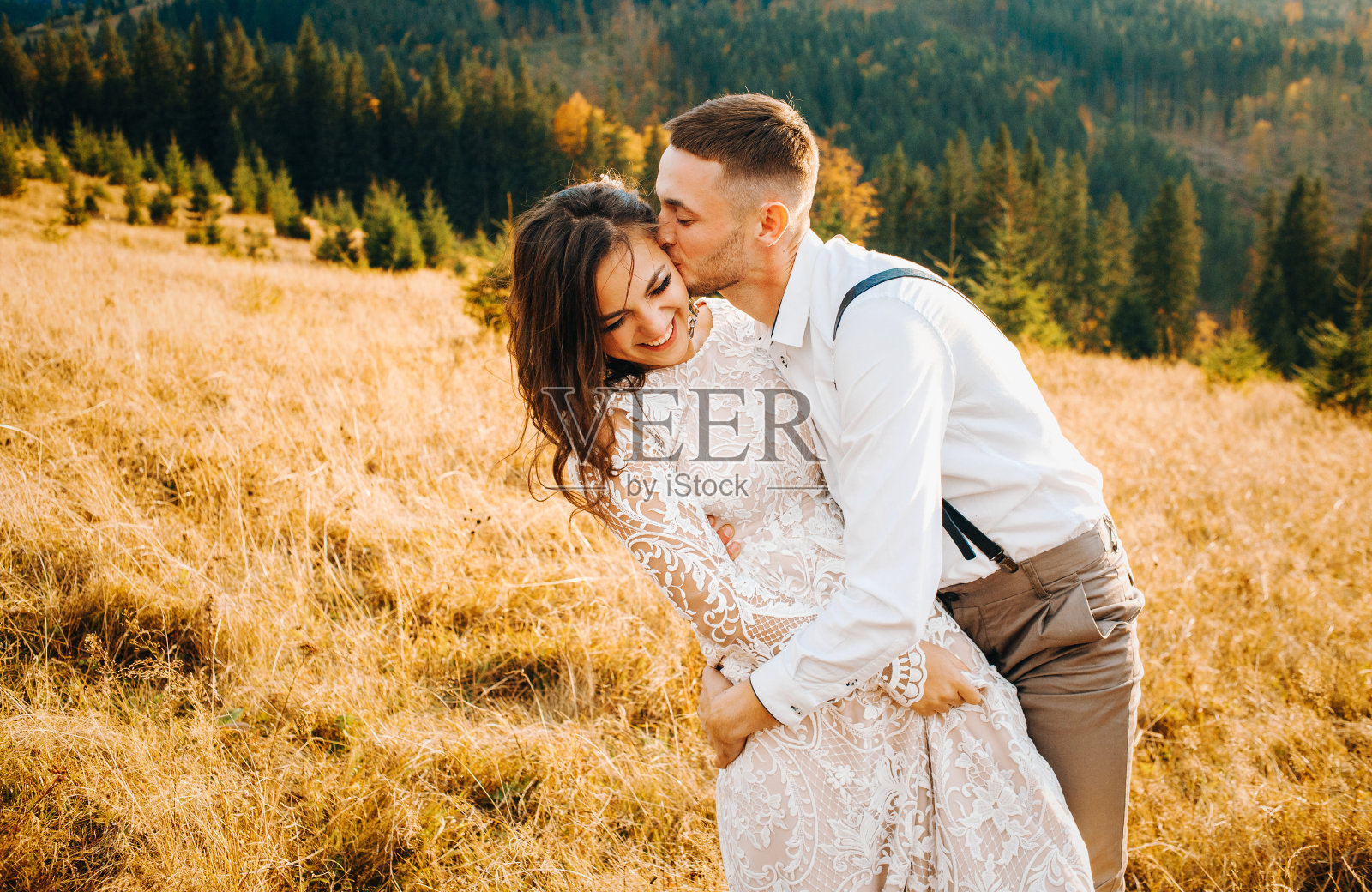 日落时分，新郎亲吻他的妻子照片摄影图片